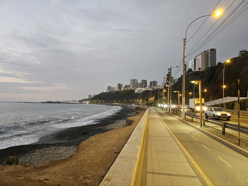 A beach of rocks next to a freeway below cliffs