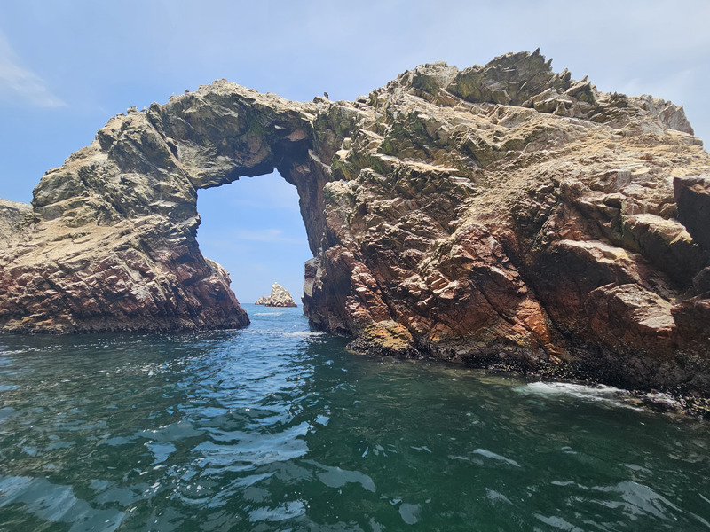 A stone arch highlighting another island in the background Islas Ballestas